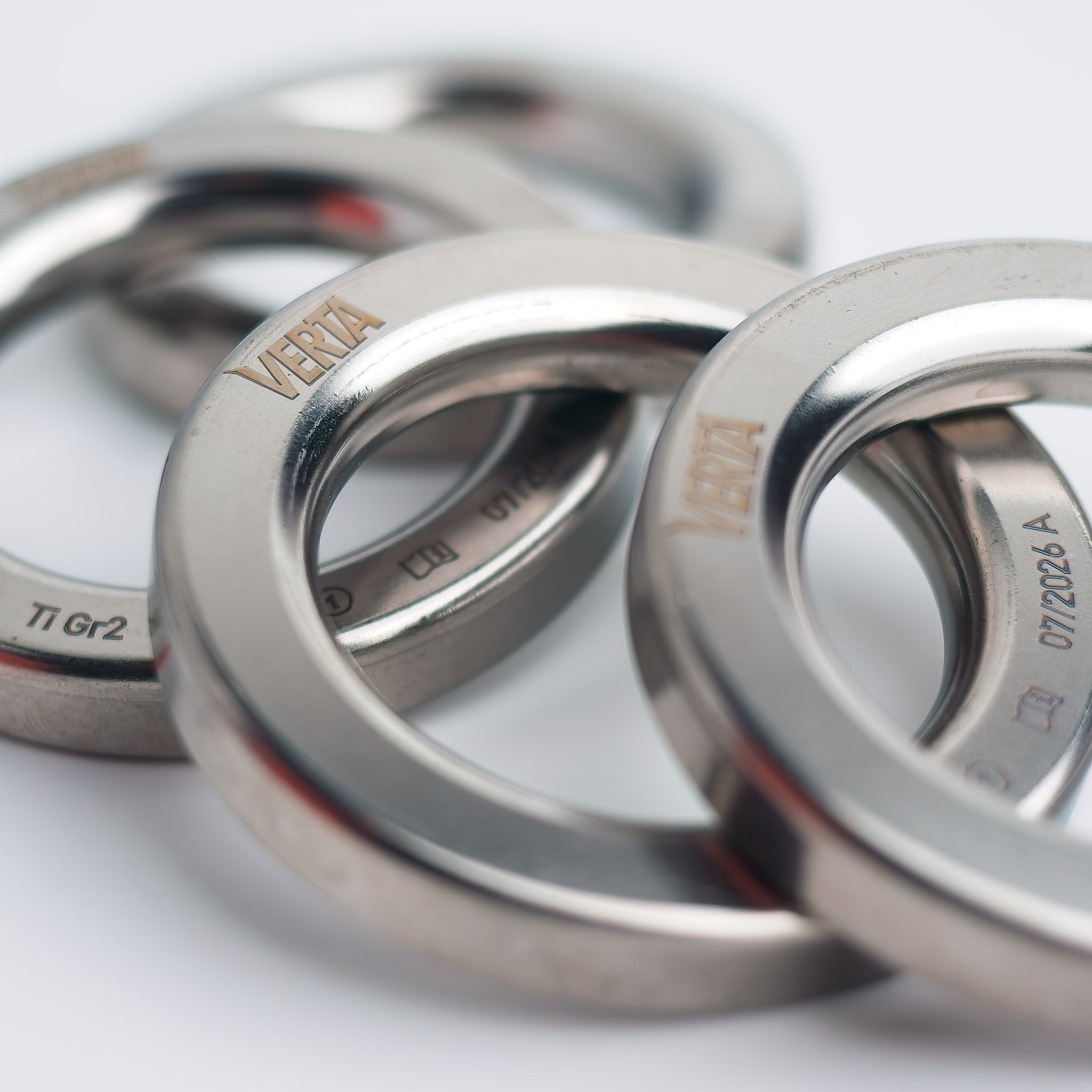 Stacked forged titanium lower-off rings showing the rounded interior profile